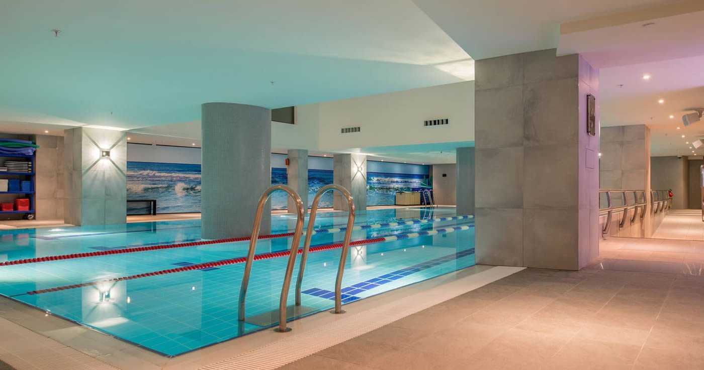 Luxurious indoor swimming pool with columns and wall art