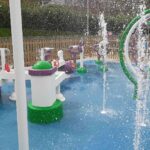 Green, white and purple water jets, buckets, and arches spraying water